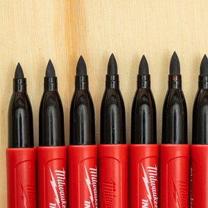 May include: Eight red and black permanent markers with a chisel tip. The markers have the word "Milwaukee" printed on the side.