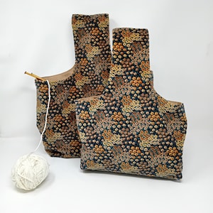 May include: Two fabric tote bags with a floral pattern in shades of brown, orange, and blue. The bags have a drawstring closure and are made of a soft, textured fabric.
