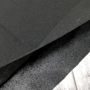 Könnte beinhalten: Zwei Stücke schwarzer Stoff, eines mit glatter Textur und das andere mit einer strukturierten Oberfläche.