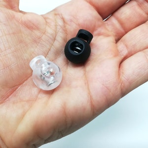 Puede incluir: Dos cierres de cordón de palanca, uno negro y otro de plástico transparente.