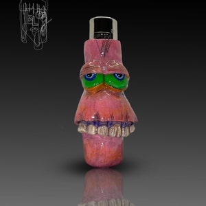 Peut inclure: Un briquet rose peint à la main avec un design de visage de dessin animé. Le briquet présente des yeux verts, un nez orange et des dents. Le haut du briquet est argenté et porte l'inscription "LIPPER". Une esquisse d'un visage est en arrière-plan.