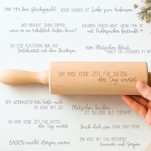 May include: A wooden rolling pin with the text "ICH HABE KEINE ZEIT FÜR DIÄTEN der Teig wartet" engraved on it. The rolling pin is held by a person's hand. The background includes Christmas decorations.