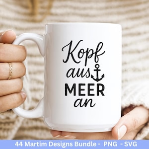 Op de afbeelding: Een witte keramische mok met een zwart nautisch ontwerp. De mok heeft de woorden "Kopf aus Meer an" in een stijlvol lettertype, met een ankersymbool. De mok wordt door een persoon vastgehouden.