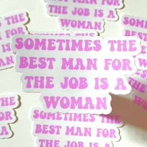 May include: Pink and white sticker with the text "Sometimes the best man for the job is a woman".