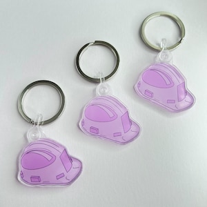 May include: Three keychains featuring a light purple construction helmet design. Each keychain has a silver-colored ring. The helmet design is a light purple color with darker purple outlines.