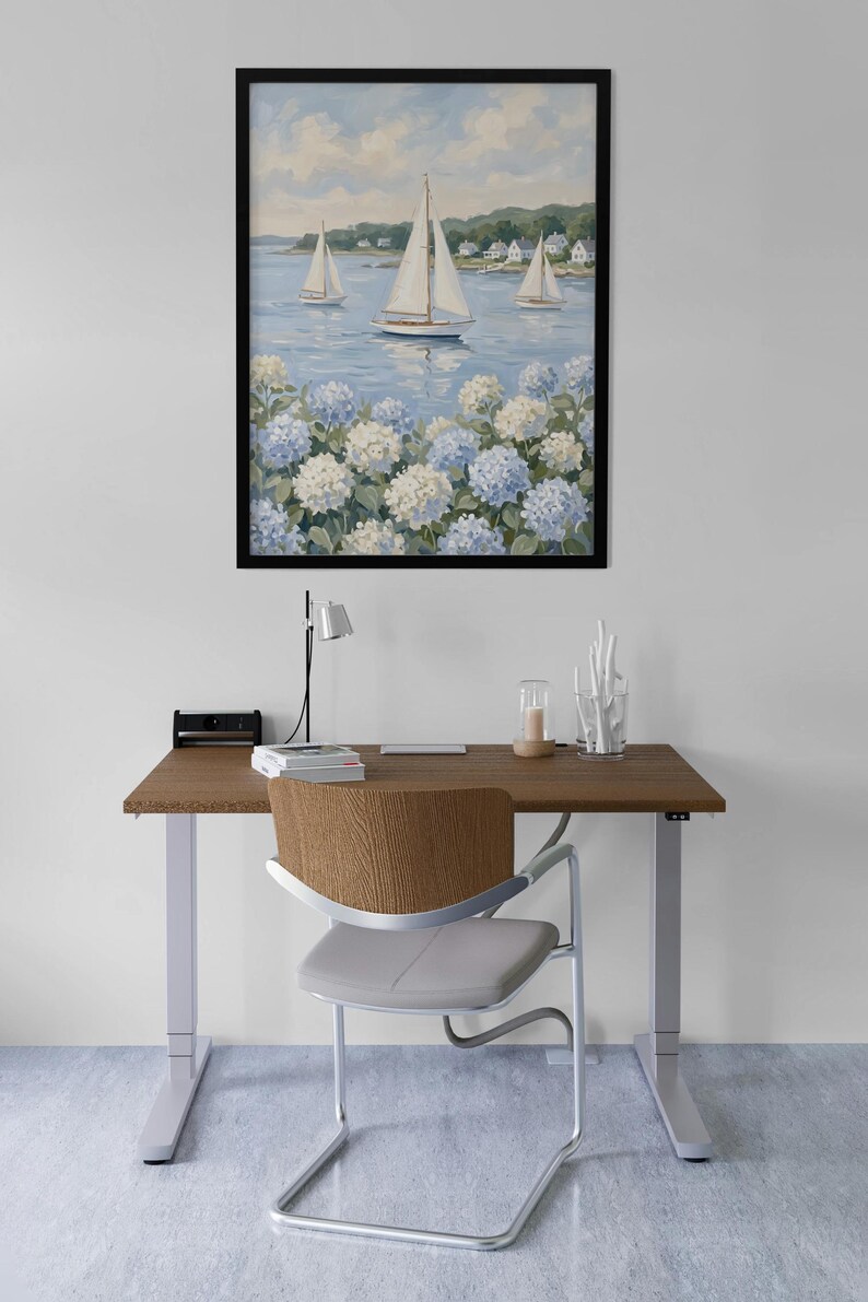 May include: A framed painting of sailboats on the water with white sails, blue water, and white and blue flowers in the foreground. The painting hangs above a wooden desk with a chair.