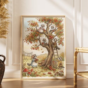 May include: A framed watercolor print depicts raccoons harvesting apples from a tree. The raccoons, dressed in various outfits, are climbing the tree, using a ladder, and collecting apples in baskets. The artwork has a warm, autumnal color palette with a whimsical, storybook feel.