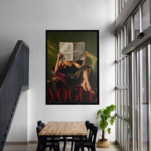 May include: A framed print of a woman reading a newspaper with the word "VOGUE" in red. The woman is seated in a red chair, holding a cigarette. The print is displayed in a modern interior with a wooden table and black chairs.
