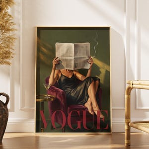 May include: A framed art print featuring a person in a black dress seated in a burgundy armchair, reading a newspaper and smoking a cigarette. The word "VOGUE" is displayed in large red letters. A martini glass sits on a small side table.