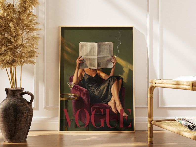 May include: A framed art print featuring a person in a black dress seated in a burgundy armchair, reading a newspaper and smoking a cigarette. The word "VOGUE" is displayed in large red letters. A martini glass sits on a small side table.