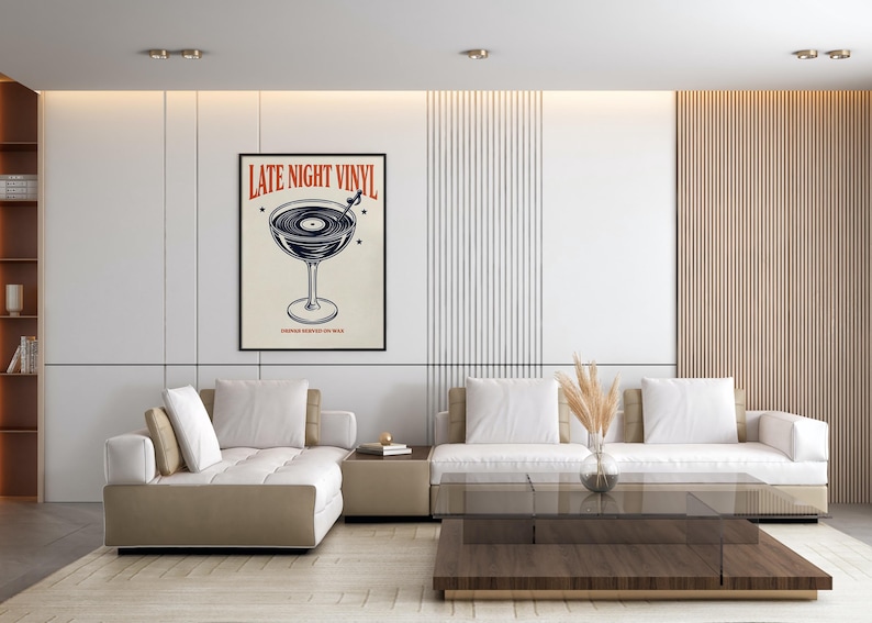 May include: A framed poster with the text "LATE NIGHT VINYL" in red and a graphic of a vinyl record in a cocktail glass. The poster is displayed in a modern living room with a white and beige color scheme.