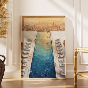 May include: A framed art print depicts a rooftop pool scene with swimmers and sunbathers. The artwork features a vibrant blue pool, white lounge chairs, and a cityscape in the background. The painting is in a wooden frame and is displayed indoors.