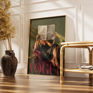 May include: A framed art print featuring a woman in a black dress, seated in a red velvet chair, reading a newspaper with the word "VOGUE" in large red letters. A martini glass sits on a small table. A decorative vase with dried plants is on the left.