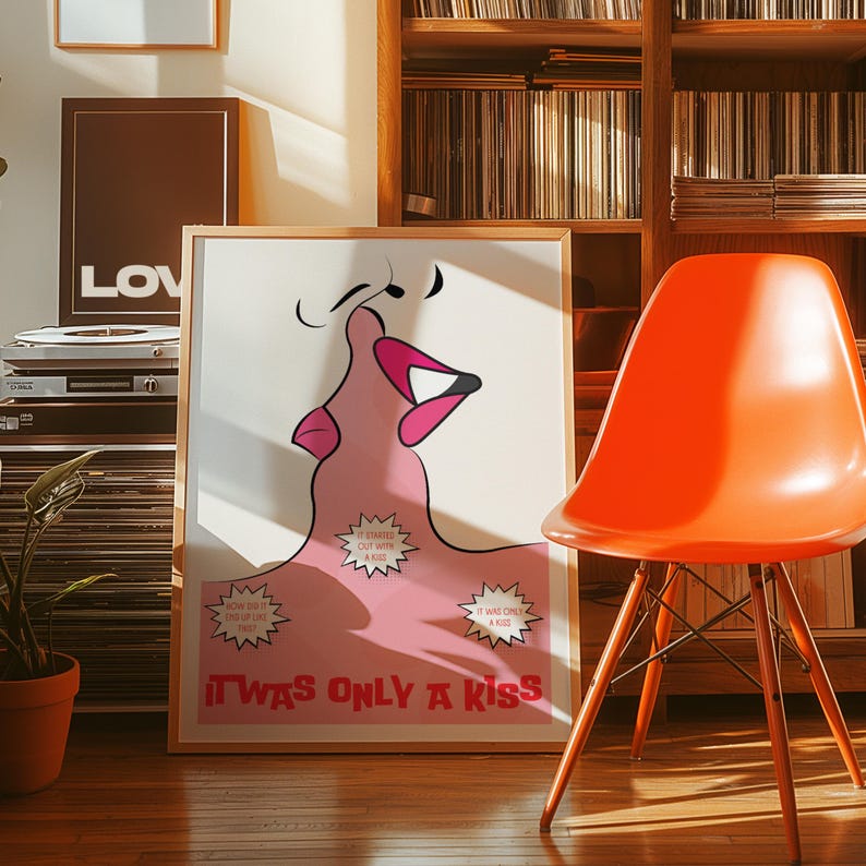 May include: A framed art print with a pink lip illustration and the text "IT WAS ONLY A KISS" in red. An orange chair and a record player are visible in the background, alongside a wooden bookcase.