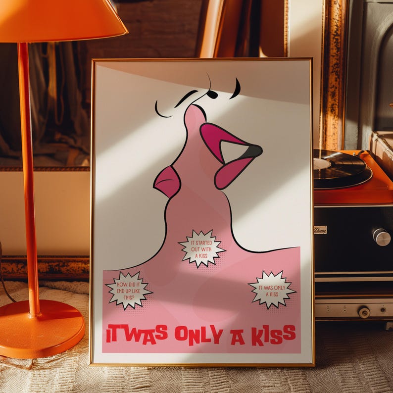 May include: Framed art print with a pink and white illustration of two lips kissing. The artwork includes the text "IT WAS ONLY A KISS" in red. The print is in a gold frame and has a minimalist style.