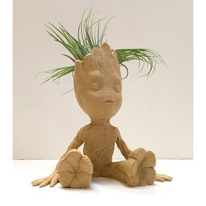 May include: A brown ceramic planter shaped like a sitting figure from the movie Guardians of the Galaxy. The planter has a small plant growing out of the top of its head.