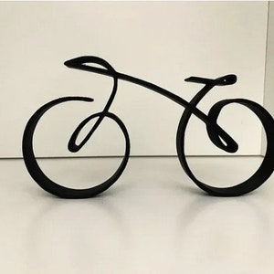 May include: A black metal sculpture of a bicycle with a curved frame and wheels. The sculpture is on a white surface.