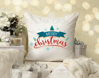 Puede incluir: Cojín cuadrado blanco con las palabras "MERRY christmas" en escritura roja, una pancarta turquesa y un árbol de Navidad verde. El cojín está decorado con copos de nieve y hojas. El fondo está borroso con decoraciones navideñas.