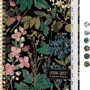 May include: A spiral-bound academic planner for 2026-2027, featuring a black cover adorned with a floral pattern in shades of green, pink, and white. The planner has monthly tabs and a gold spiral binding.