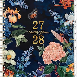 May include: A spiral-bound planner with a dark blue background, adorned with colorful floral illustrations and a butterfly. The cover features the gold text "27 Monthly Planner 28" and monthly tabs. The design includes orange, blue, pink, and white flowers.