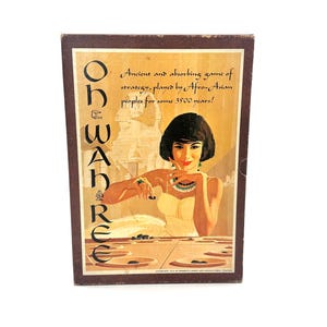 May include: A vintage game box with a brown background and a woman in a white dress playing a game. The box has the text "Oh Wah Ree" and "Ancient and absorbing game of strategy, played by Afro-Asian peoples for some 3500 years!" printed on it.