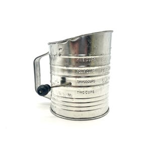 May include: Silver metal flour sifter with a crank handle. The sifter has markings for 2, 3, 4, and 5 cups.