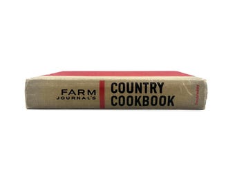 May include: A vintage cookbook titled "Farm Journal's Country Cookbook" with a red spine and tan cover. The text is in black, with the publisher's name, Doubleday, visible on the edge. The book is closed and lying flat.