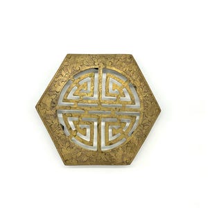 May include: A gold-colored, hexagonal decorative piece with an intricate, openwork design. The center features a stylized symbol, and the edges are adorned with floral patterns. This item is likely a decorative element for home decor.
