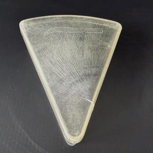 May include: A clear, triangular-shaped glass plate with a textured surface. The plate has a rounded edge and a design etched into the glass. The plate is a light, translucent color.