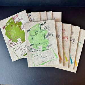 May include: A collection of vintage sewing books titled "Simplified Systems of Sewing and Styling" by Doris Anderson. The covers feature green and red illustrations and text on a beige background. The books are arranged on a dark surface.