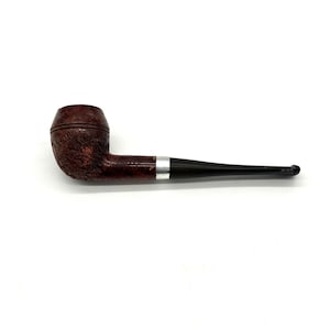 May include: A brown tobacco pipe with a textured bowl and a dark stem. The pipe has a silver band near the stem's connection to the bowl. The stem is black and has a curved mouthpiece. The pipe is set against a white background.