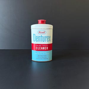 May include: Vintage Denturex false teeth cleaner tin. The cylindrical tin has a white body with a red band and blue accents. The text on the tin reads "Denturex False Teeth Cleaner" and lists benefits like deodorizing and removing stains.