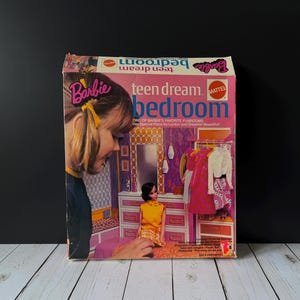 May include: A vintage Barbie "teen dream bedroom" playset box. The box is pink and features an illustration of a Barbie doll in a bedroom setting. The text "Barbie teen dream bedroom" is prominently displayed.