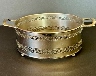 Pode incluir: Uma travessa redonda prateada com duas pegas. A travessa apresenta um design decorativo vazado nas laterais e assenta em três pequenos pés. O design é vintage e elegante.