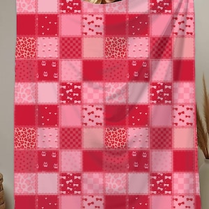 May include: A red and pink patchwork blanket with various patterns, including hearts, bows, and leopard print. The blanket is displayed, showcasing its square design and color variations.