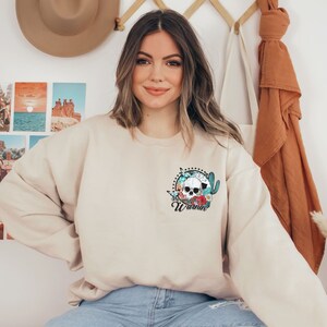 May include: A beige sweatshirt with a floral skull graphic and the word "Wornin'" printed on the front.