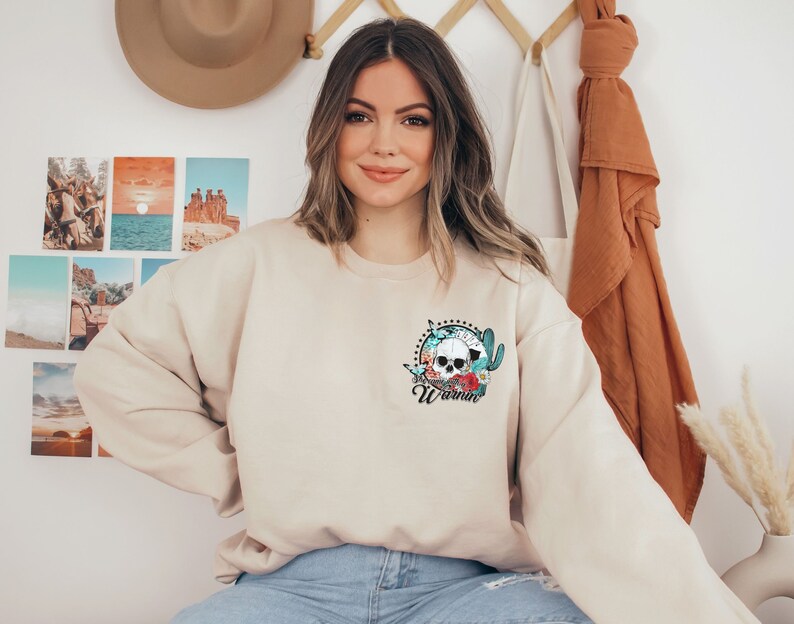 May include: A beige sweatshirt with a floral skull graphic and the word "Wornin'" printed on the front.