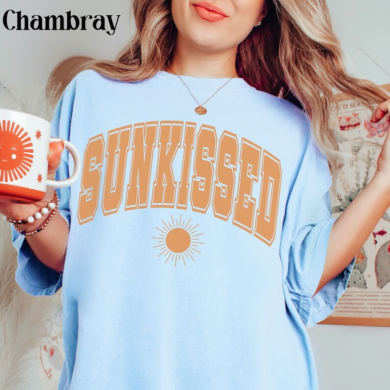 May include: A light blue t-shirt with the text "SUNKISSED" in orange with a stylized sun graphic below.
