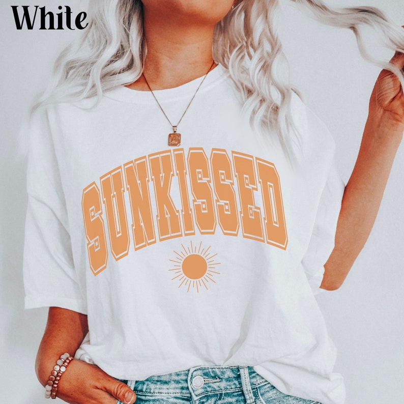 May include: White t-shirt with the text "SUNKISSED" in orange with a stylized sun graphic below.