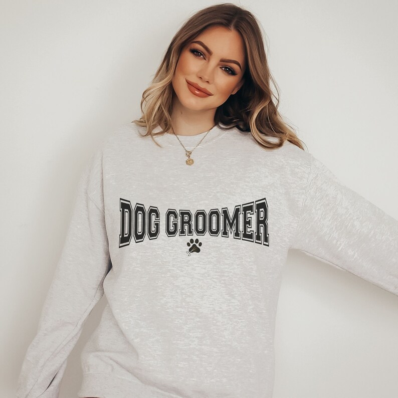 May include: A heather gray sweatshirt with the text "DOG GROOMER" in black with a paw print below.