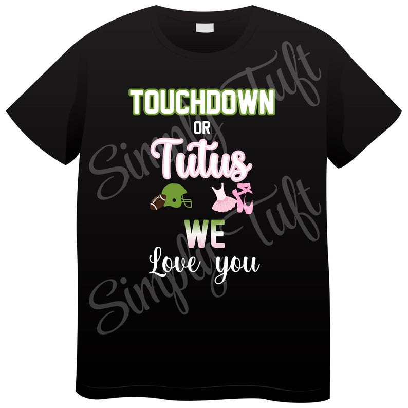 Op de afbeelding: Zwart T-shirt met de tekst "Touchdown or Tutus We Love You" in groen en roze. Een voetbalhelm en een paar roze balletten zijn afgebeeld.