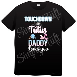K&ouml;nnte beinhalten: Schwarzes T-Shirt mit dem Text "Touchdown oder Tutu Daddy Loves You" in Blau, Rosa und Wei&szlig;. Ein Footballhelm und ein rosa Tutu mit Ballettschuhen sind abgebildet.