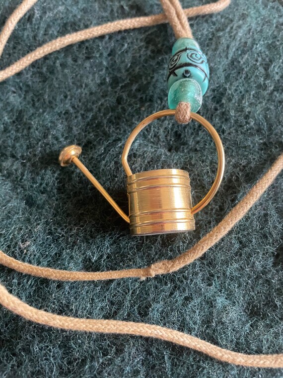 Watering can necklace.