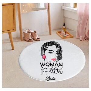 May include: Round white rug with a black and white illustration of a woman with braids, pink earrings, and red lips. The text "WOMAN OF faith Linda" is printed below the illustration.