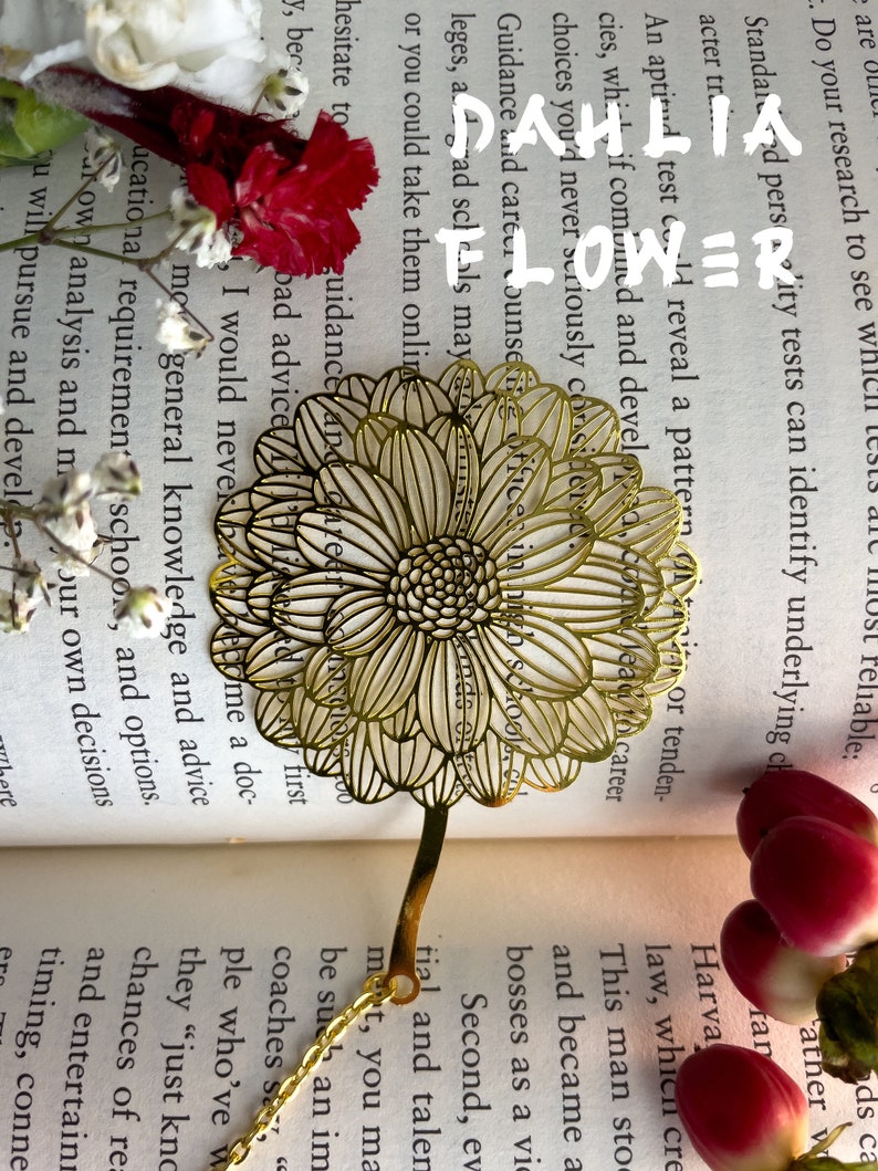 May include: A gold metal bookmark shaped like a dahlia flower. The bookmark is on top of an open book with text about career guidance and education.