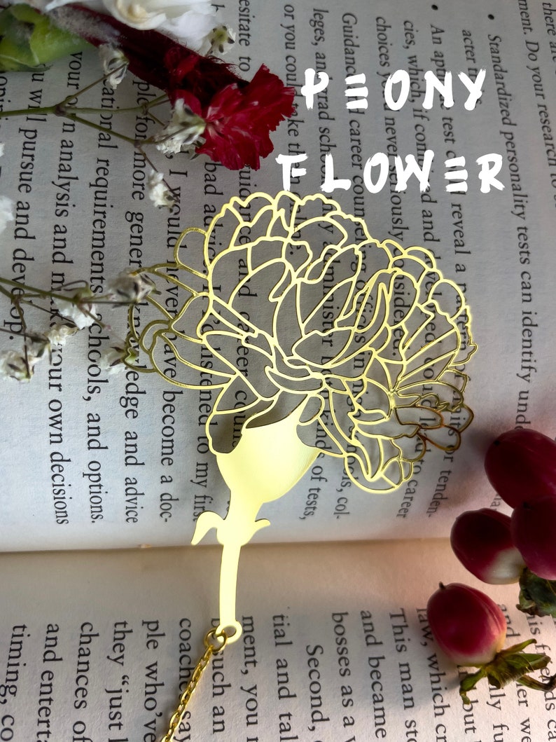 May include: A gold metal bookmark shaped like a peony flower. The bookmark is on top of a book with text about career counseling and standardized personality tests.