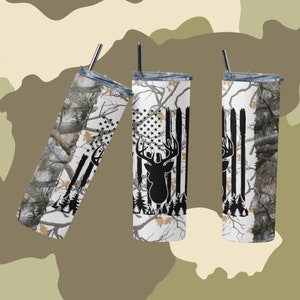May include: Three stainless steel tumblers with a white background and a camouflage pattern. The tumblers feature a black silhouette of a deer head with antlers and an American flag design.