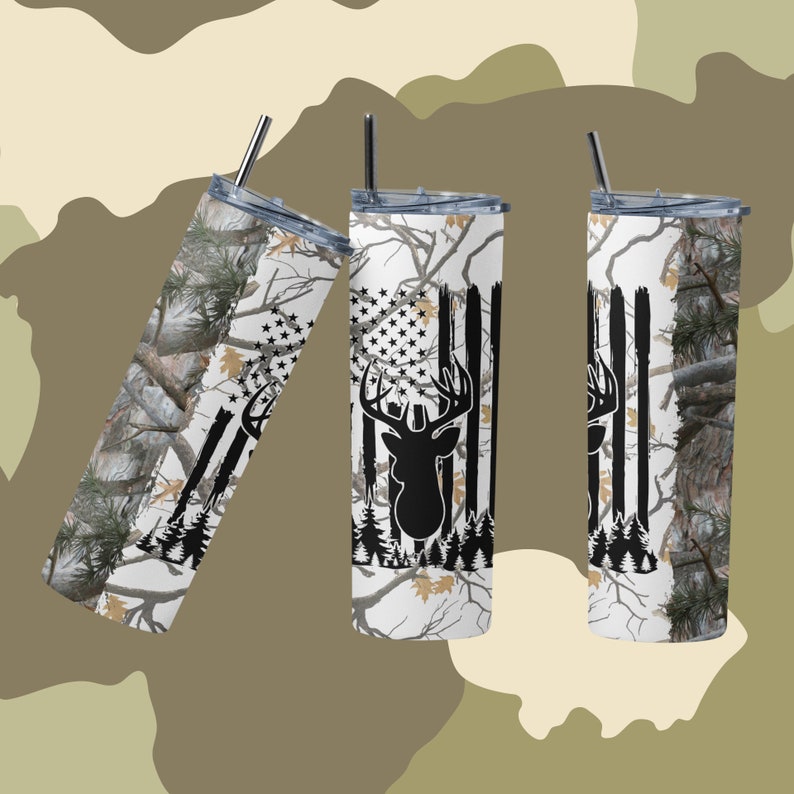 May include: Three stainless steel tumblers with a white background and a camouflage pattern. The tumblers feature a black silhouette of a deer head with antlers and an American flag design.
