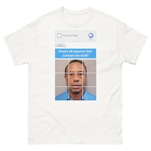 May include: White t-shirt featuring a humorous graphic. The graphic mimics a CAPTCHA test, with the text "I'm not a robot" and "Select all squares that contain the GOAT" above a grid with a photo of Tiger Woods.