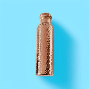 Pu&ograve; includere: Una borraccia color rame con una texture martellata. La bottiglia ha una base arrotondata e un tappo a vite. Lo sfondo &egrave; blu chiaro uniforme.